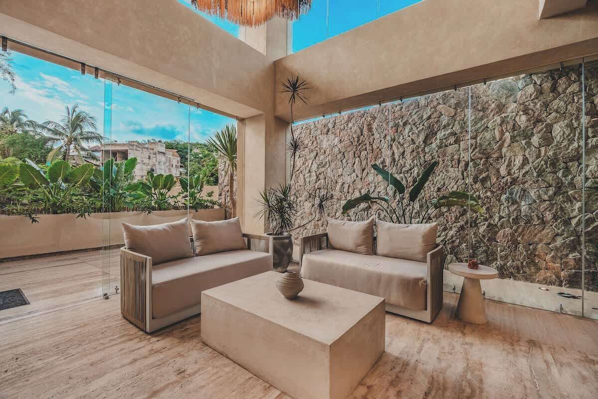 A spacious living area with a stone wall, a large window, and a view of palm trees.