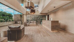 A spacious, modern lobby with a wooden floor, a curved seating area, and a reception desk. - Ceiba Tropical at Caivama (Sayulita)