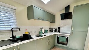 A modern kitchen with a skylight, herringbone wood flooring, and a built-in microwave.
