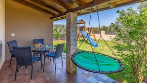 An outdoor patio with a dining table and chairs, a swing, and a slide in the background. - Awesome home in Pula with WiFi (Pula)