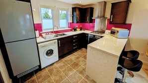 A compact kitchen with a washing machine, a sink, a stove, and a microwave.