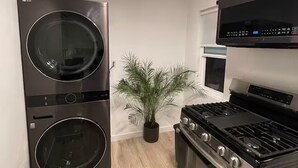 A compact kitchen with a double washer-dryer unit, a stove, and a microwave.