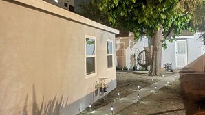 A building with a beige exterior, a tree in front, and a paved pathway with ground markers.