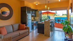 A modern kitchen with stainless steel appliances, a dining area with a table and chairs, and a large window overlooking a blue building. - Beach Break Suites Private Villa – Downtown | 5 Suites & Private Pool (Sayulita)