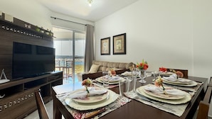 A dining area with a large table set for four, a television, and a sofa.
