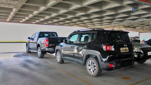 Un estacionamiento con vehículos, incluyendo un SUV negro y una camioneta.