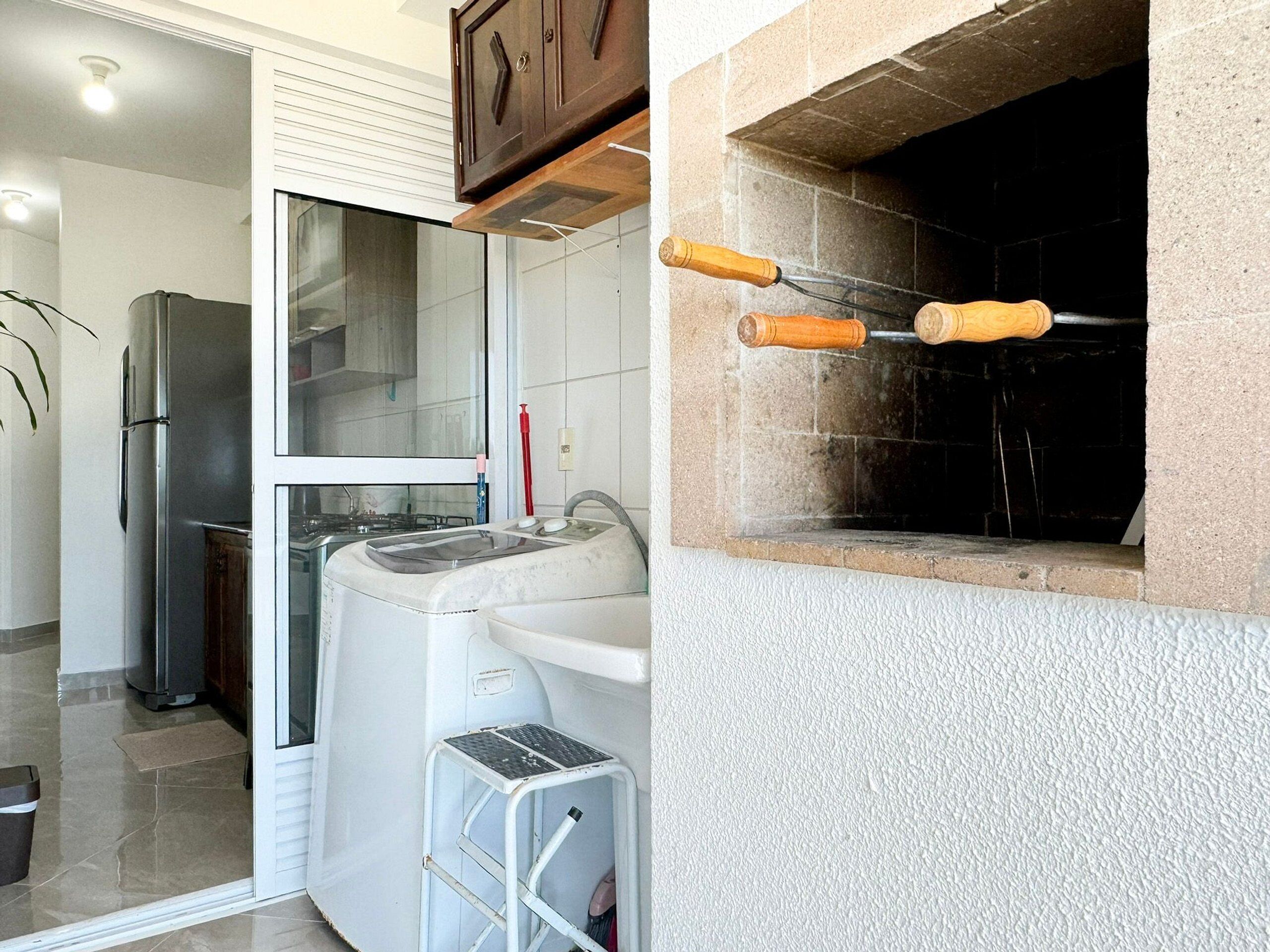 Eine Küche mit Kühlschrank, Waschmaschine und einer kleinen Stufe.