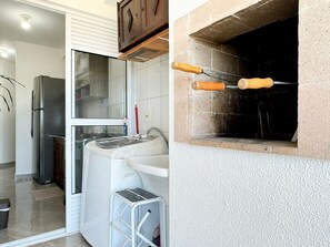 A kitchen with a refrigerator, washing machine, and a small step stool. - Resid. Clube Mar Grosso-Laguna - LAG801 (Laguna)