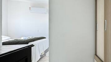Une chambre à coucher comprenant un lit, une armoire et un climatiseur fixé au mur.