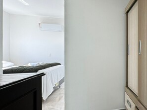 A bedroom with a bed, a wardrobe, and a wall-mounted air conditioner. - Resid. Clube Mar Grosso-Laguna - LAG801 (Laguna)