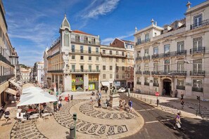 A public square with a circular pavement design, surrounded by historic buildings with balconies and a prominent clock tower. - Charming City Center (Lisbon)