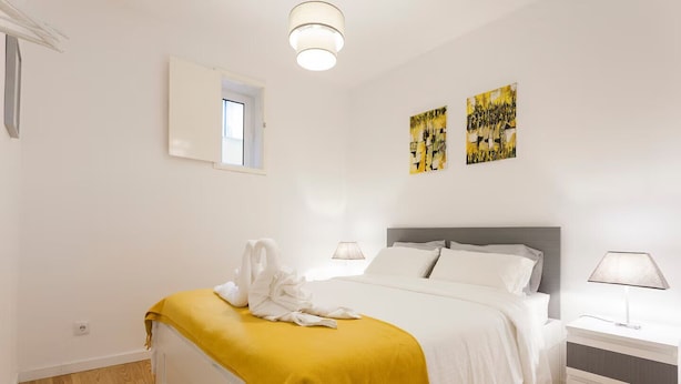 Ein Schlafzimmer mit Bett, Nachttischen, einem Fenster und Bildern an der Wand.