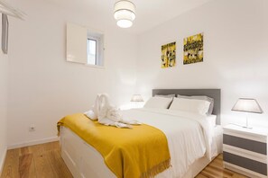 Een slaapkamer met een bed, nachtkastjes, een raam en kunst aan de muur.