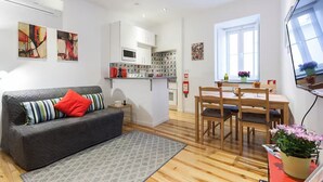 Ein kompakter Wohnbereich mit Sofa, Esstisch und Küchenzeile.