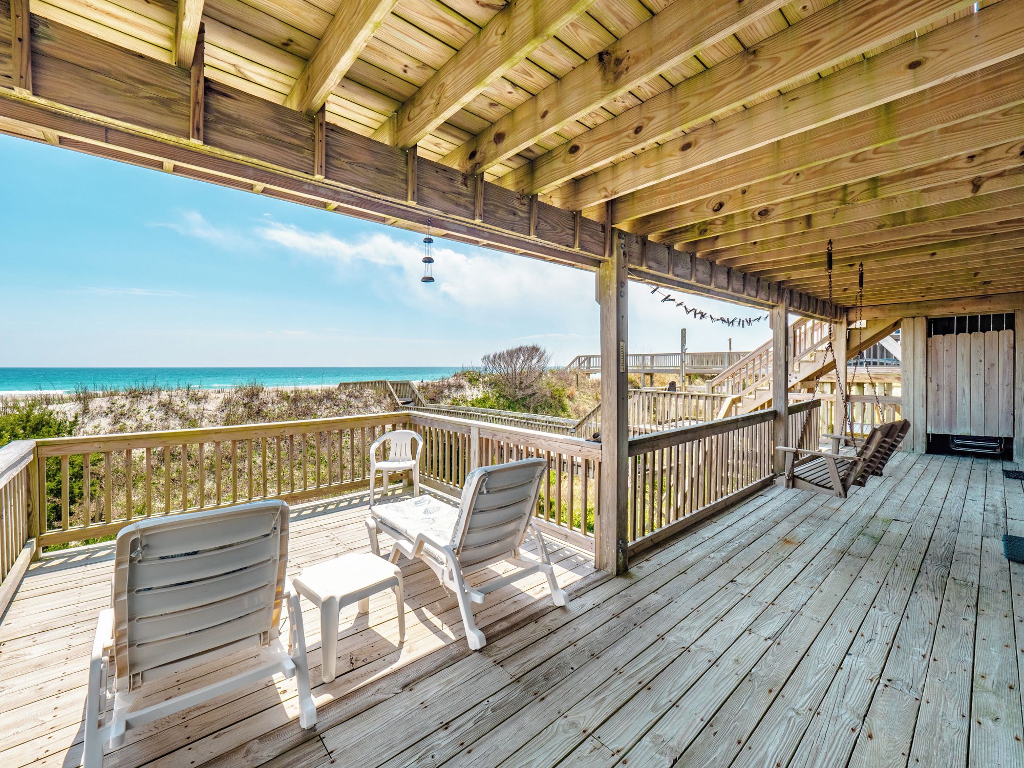 A wooden deck with a view of the beach and ocean.