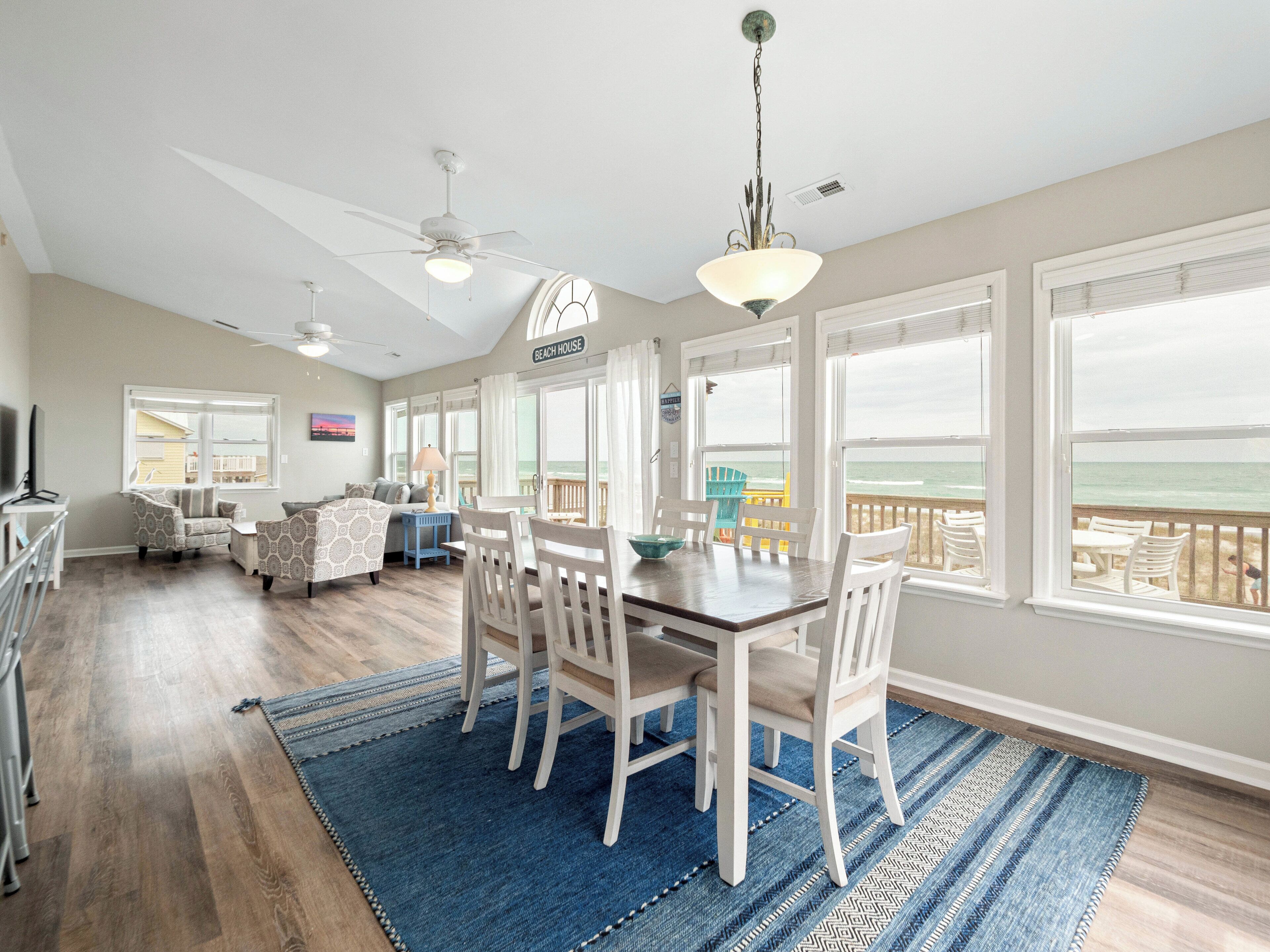 A spacious living room with a dining area, large windows, and a view of the ocean.