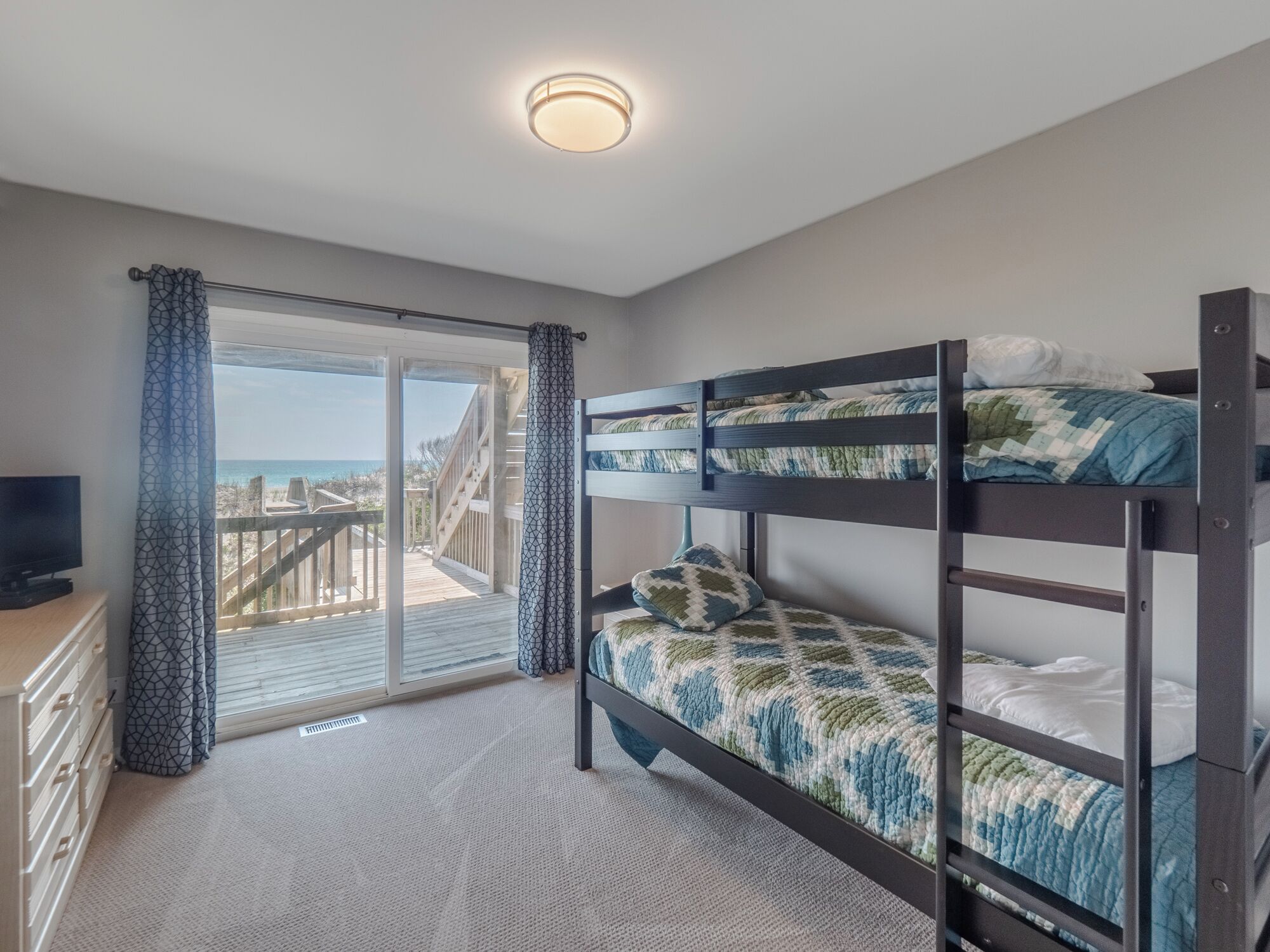 Habitación con literas y vista a la playa a través de un ventanal grande.