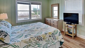 A bedroom with a bed, dresser, television, and a ceiling fan. - Costic by Topsail Realty (Holly Ridge)