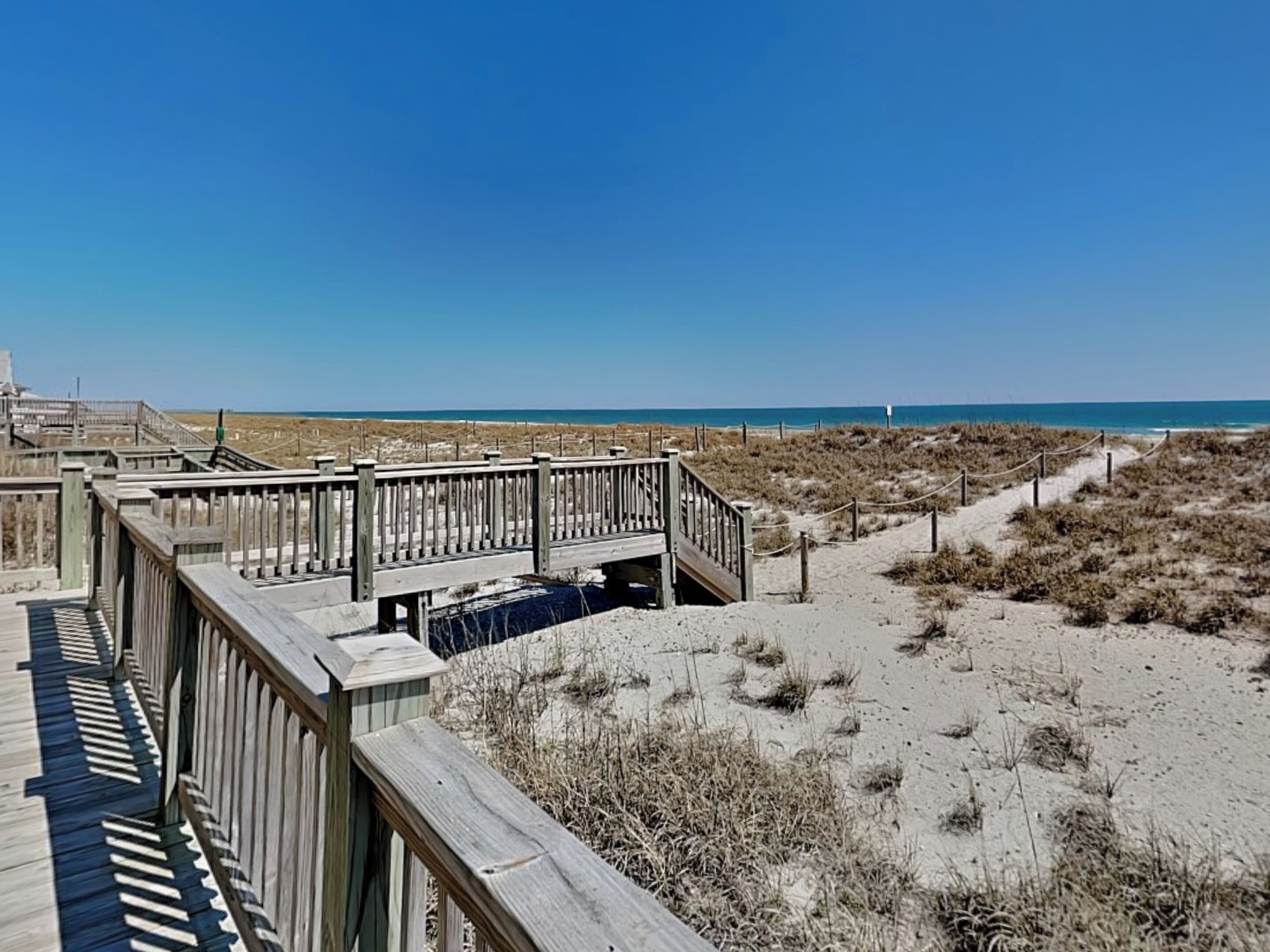 Un muelle de madera que conduce a una playa, con vista clara al océano.