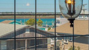 Vista a través de una ventana con diseño de cuadrícula, sobre un cuerpo de agua, un muelle y edificios de estructura de madera con un poste de servicios.