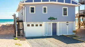 Et toetagers strandhus med blå facade, en fordør og en lille veranda.