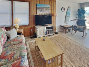 Relax in this inviting living room with a tropical-themed sofa, flat-screen TV, and a cozy reading nook.