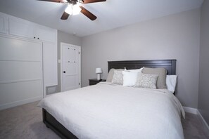A bedroom with a bed, nightstand, ceiling fan, and white wardrobe. - Designer decorated 6 bedroom 4 bath pool home (Santa Ana)