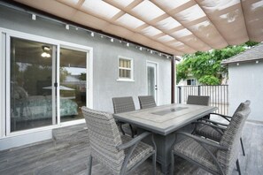 Eine überdachte Terrasse mit Esstisch und Stühlen, einer Schiebetür aus Glas und einem kleinen Fenster.
