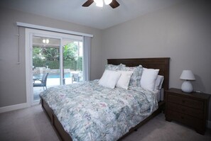 A bedroom with a bed, a nightstand, a lamp, and a sliding glass door leading to an outdoor area.