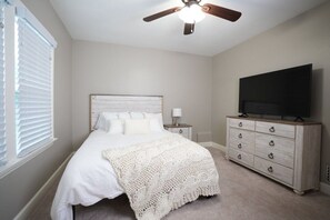 A bedroom with a bed, a dresser, a television, and a ceiling fan. - Designer decorated 6 bedroom 4 bath pool home (Santa Ana)