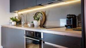 Ett modernt kök med mörka skåp, en rostfri köksfläkt och en kaffemaskin.