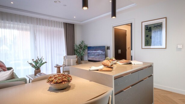 Ett modernt vardagsrum med en matplats, en tv och ett inramat konstverk på väggen.
