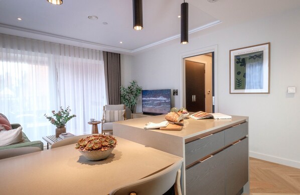 A modern living room with a dining area, a television, and a framed artwork on the wall.