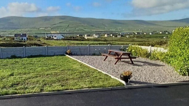 A picnic area with a bench and table, surrounded by a gravel path and greenery, overlooking a rural landscape with houses and fields. - Rustic Kerry Hideaway - Cliffs, Coast & Comfort (Valentia Island)