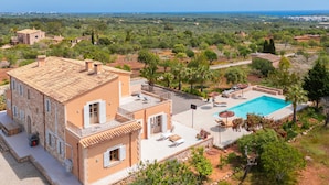 A villa with a swimming pool, outdoor seating, and a view of the surrounding landscape.