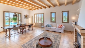 A spacious living room with a dining area, large windows, and a fireplace.