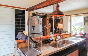 Uma cozinha com pia de aço inoxidável, cafeteira e luminária pendente.