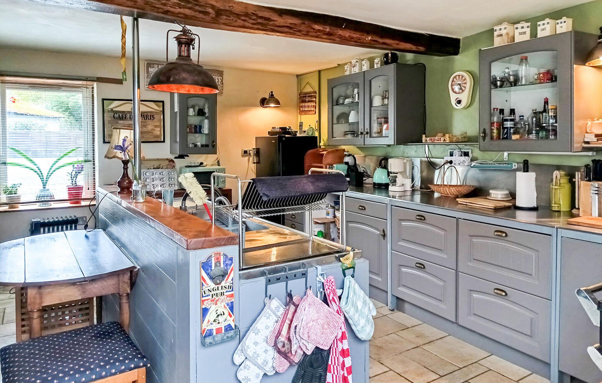 Una cocina con barra, un reloj y diversos electrodomésticos.