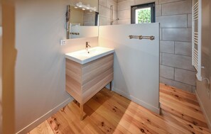 Une salle de bain moderne avec un meuble-lavabo en bois, un miroir et un espace douche.