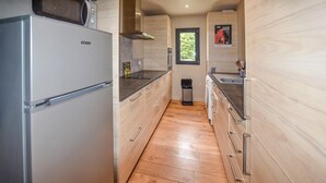 Une cuisine moderne avec des meubles en bois, un réfrigérateur en acier inoxydable et une fenêtre ornée d’une affiche.