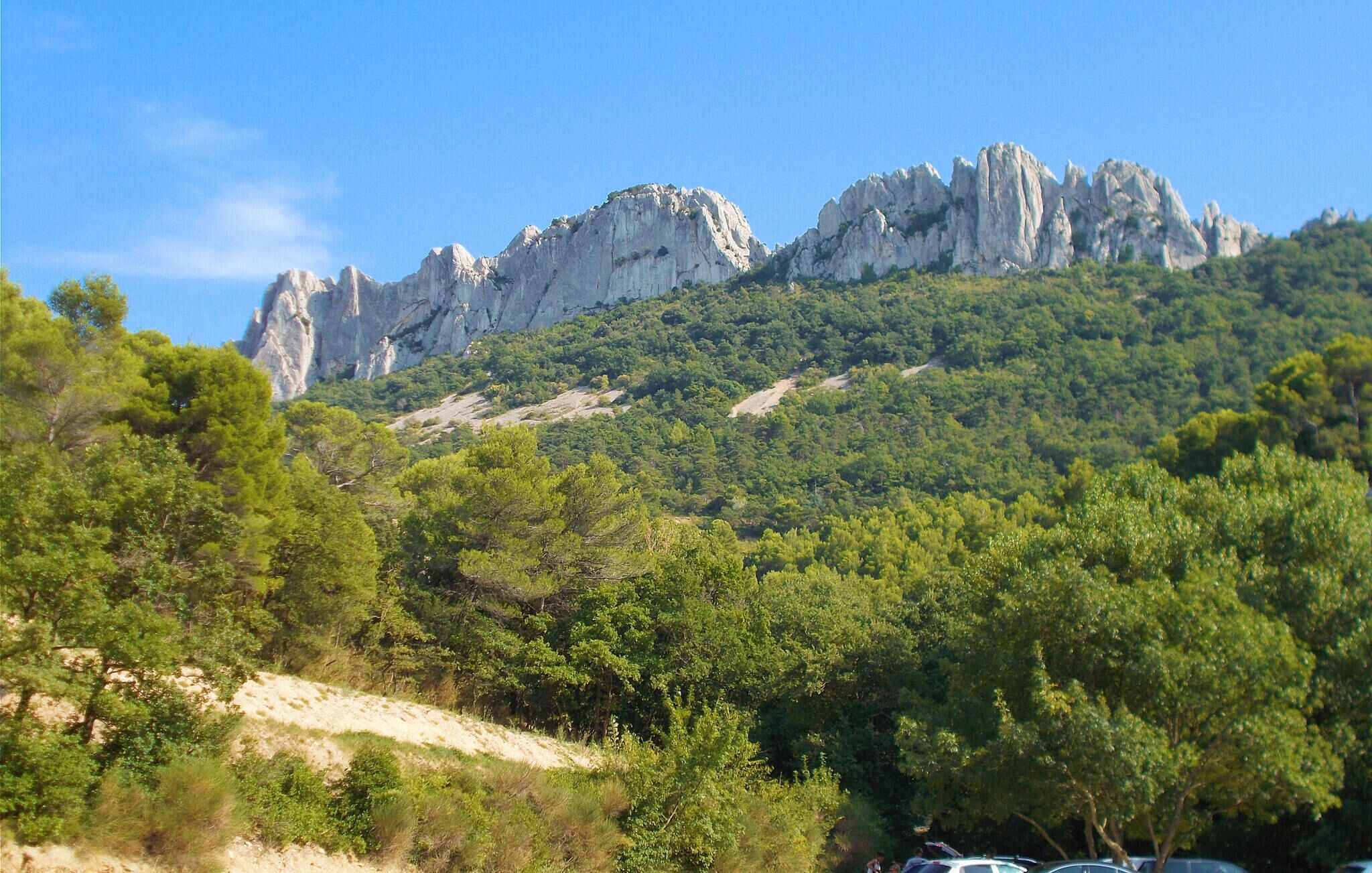 Paisagem montanhosa com penhascos rochosos e floresta verde densa.