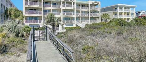 A beachfront hotel with a central walkway leading to a building with multiple balconies.