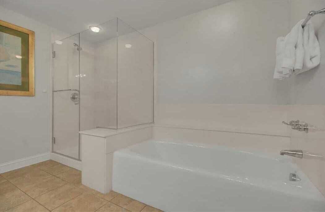 Un baño moderno con ducha de vidrio, una bañera independiente y un perchero para toallas.