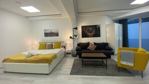 Un dormitorio moderno con cama, sofá, una mesita de centro y un ventanal grande.