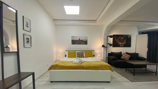 Un dormitorio moderno con una cama grande, mesitas de noche, un sofá y un escritorio.