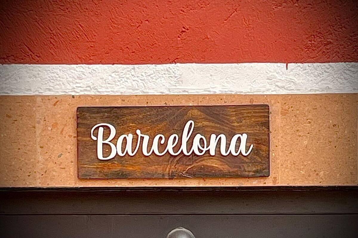 A wooden sign with the word "Barcelona" on a textured wall.