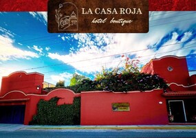 Un edificio rojo con un cartel que dice "LA CASA ROJA hotel boutique" y una pequeña ventana con un letrero.