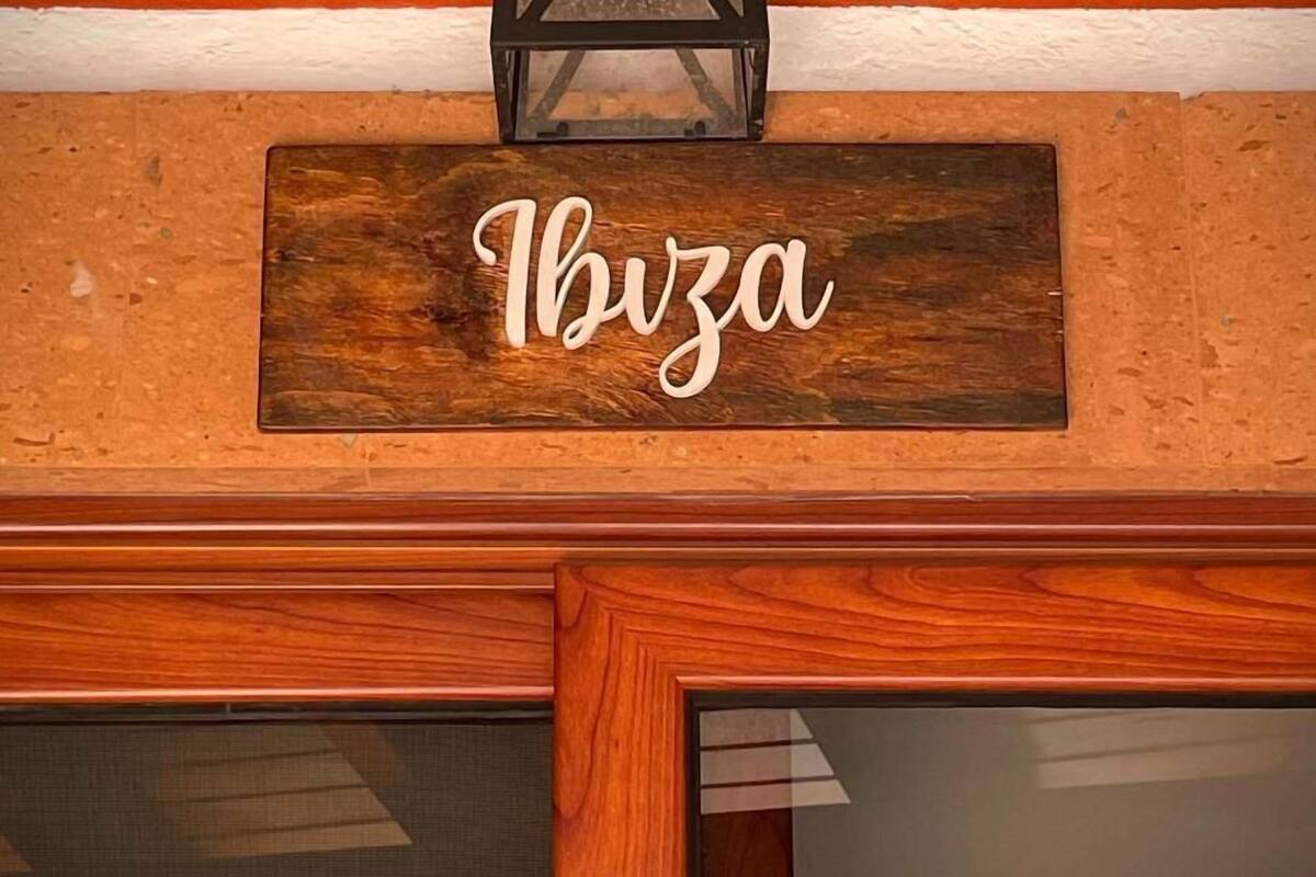 A wooden sign with the name "Ibiza" mounted on a textured wall.