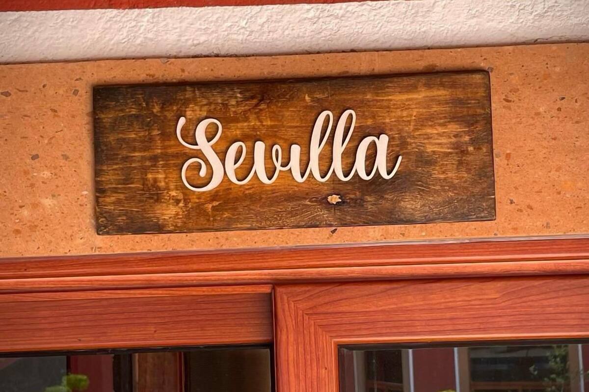 A wooden sign with the name "Sevilla" above a doorway.