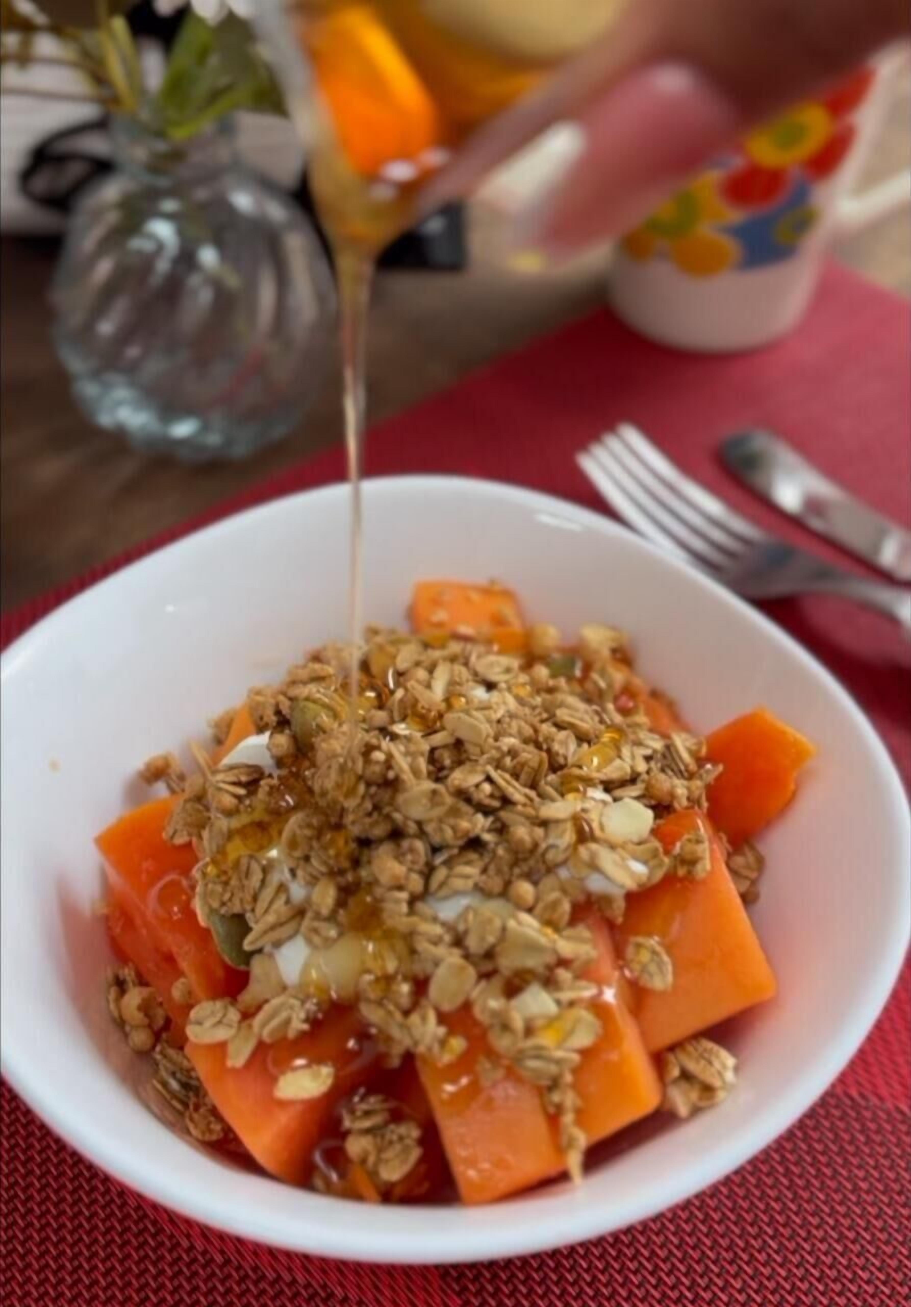 Eine Schüssel mit Granola, Honig und geschnittenen Karotten.